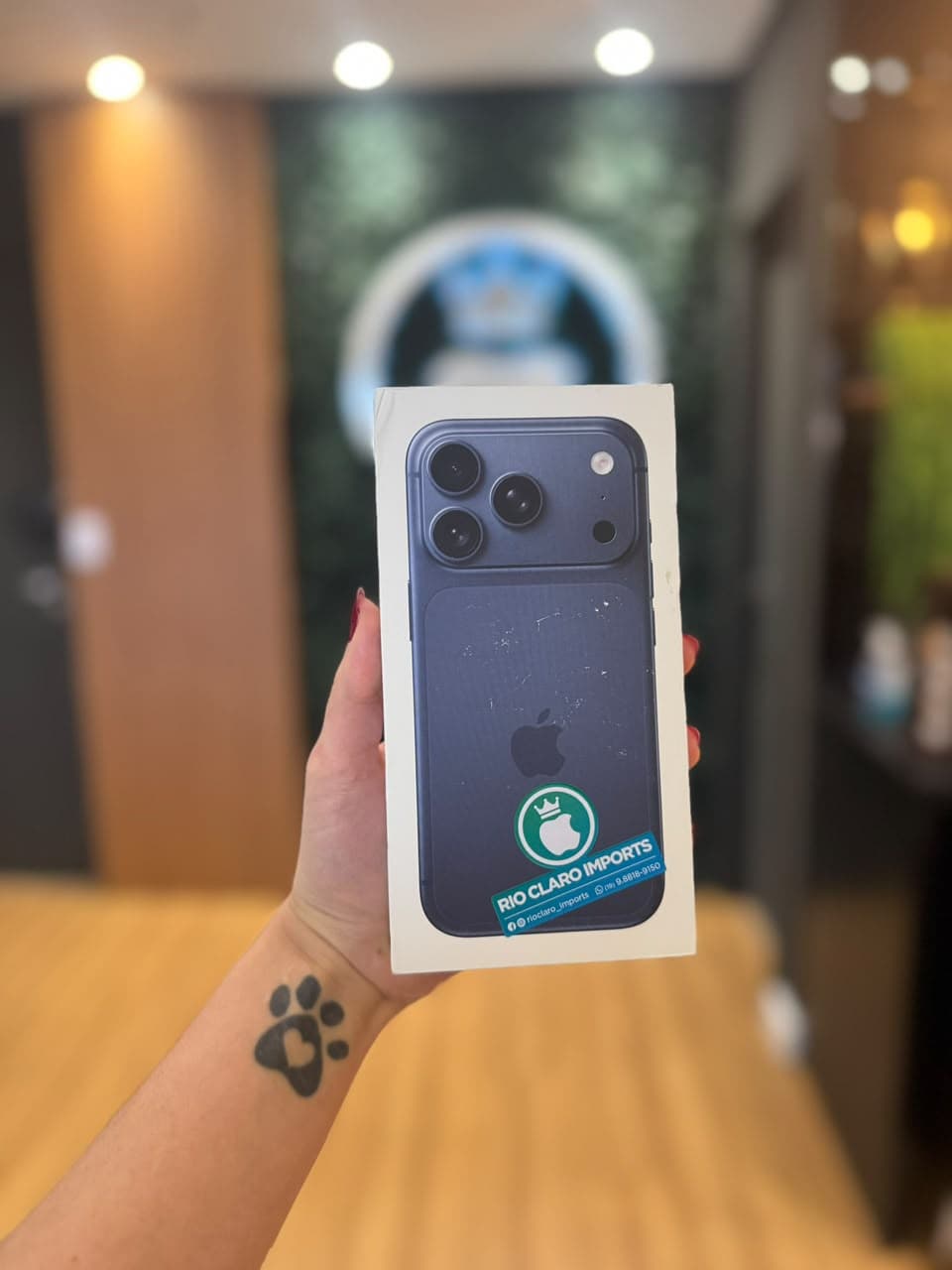 Mão segurando a caixa de um iPhone azul dentro da loja