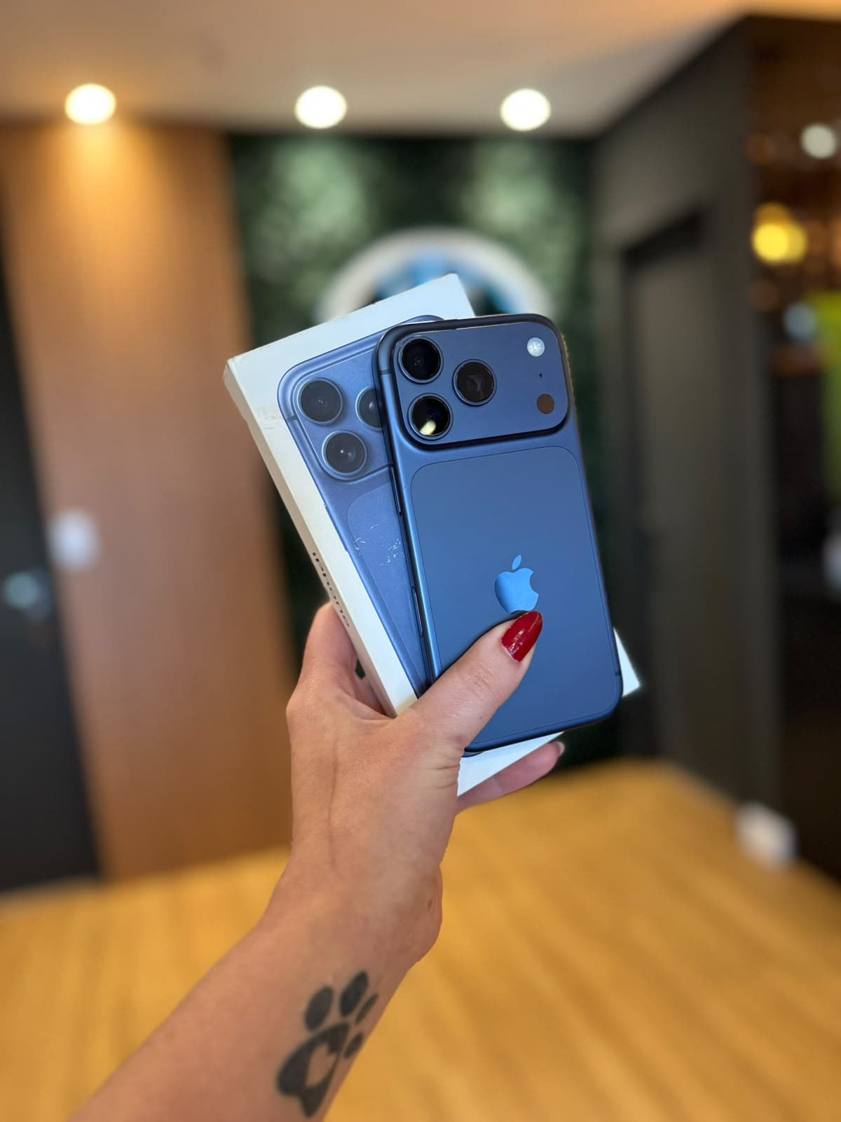 Mão segurando um iPhone azul junto da caixa original